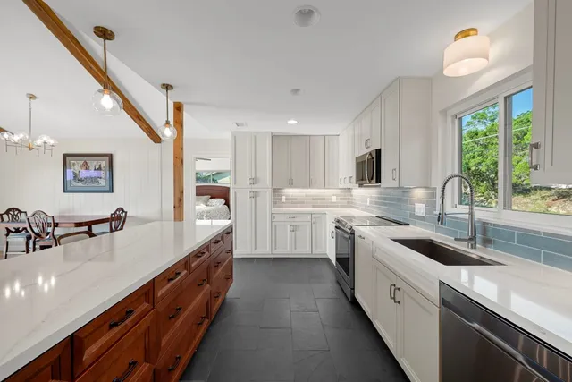a kitchen with granite countertop a sink counter top space appliances and a window