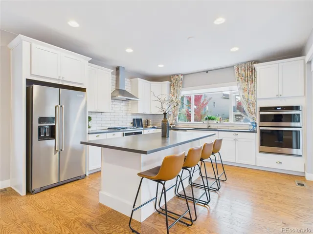 a kitchen with stainless steel appliances kitchen island granite countertop a refrigerator and a stove top oven