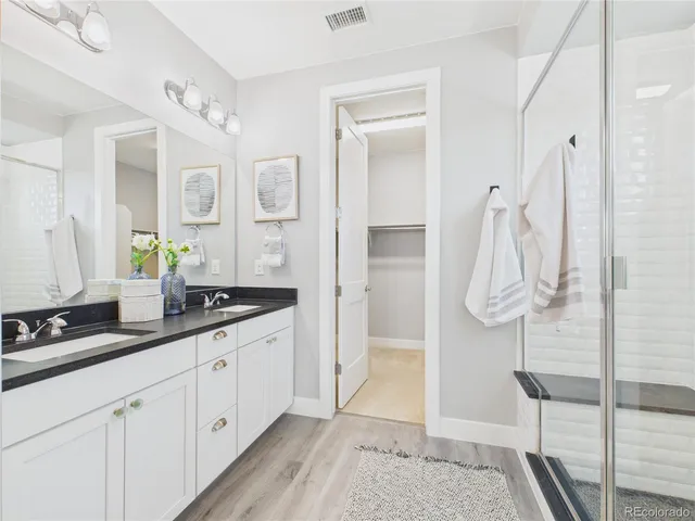 a spacious bathroom with a granite countertop sink a mirror and shower