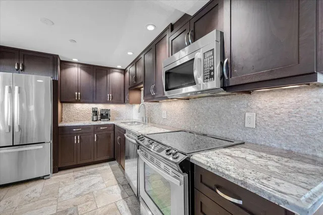 a kitchen with stainless steel appliances granite countertop a sink stove and microwave