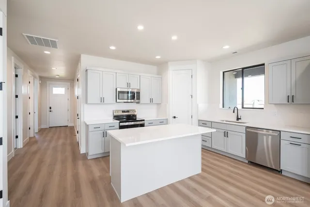 a kitchen with stainless steel appliances white cabinets and wooden floor