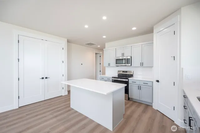 a room with a white bed cabinets and wooden floor
