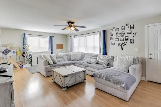 a living room with couches and a dining table with wooden floor