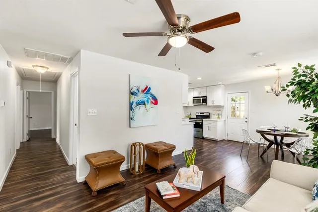 a living room with furniture kitchen view and a wooden floor