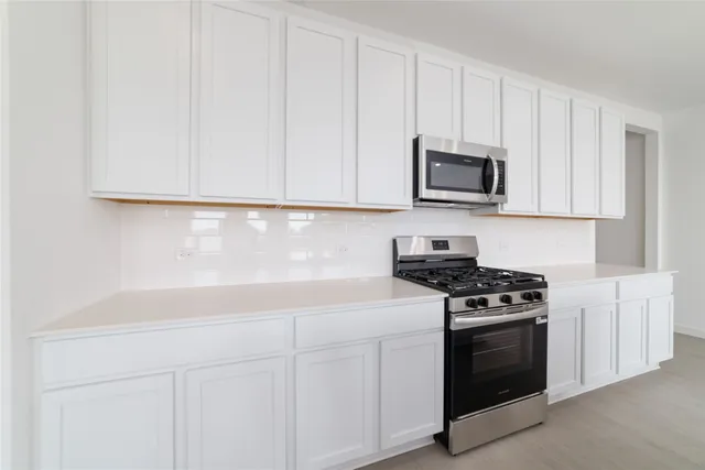 a kitchen with granite countertop white cabinets and stainless steel appliances