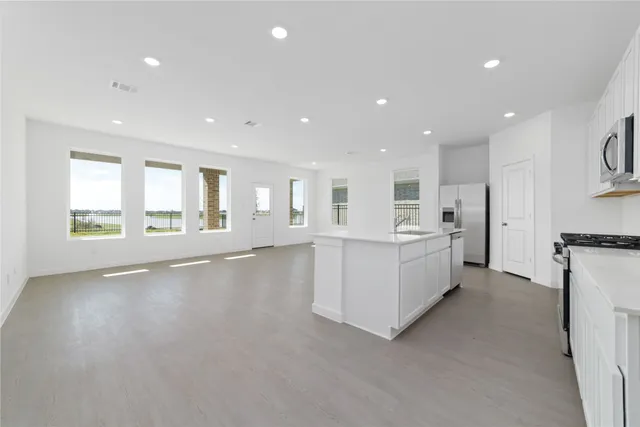 a large white kitchen with kitchen island a sink a center island stainless steel appliances and a cabinets
