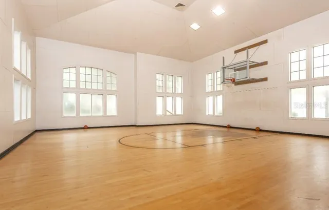 a view of a swimming pool that has lawn chairs and a dining table under an umbrella