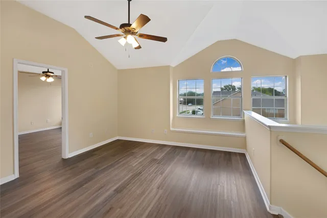 a view of an empty room with a window and wooden floor