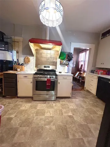 a kitchen with kitchen island a stove a sink dishwasher and white cabinets