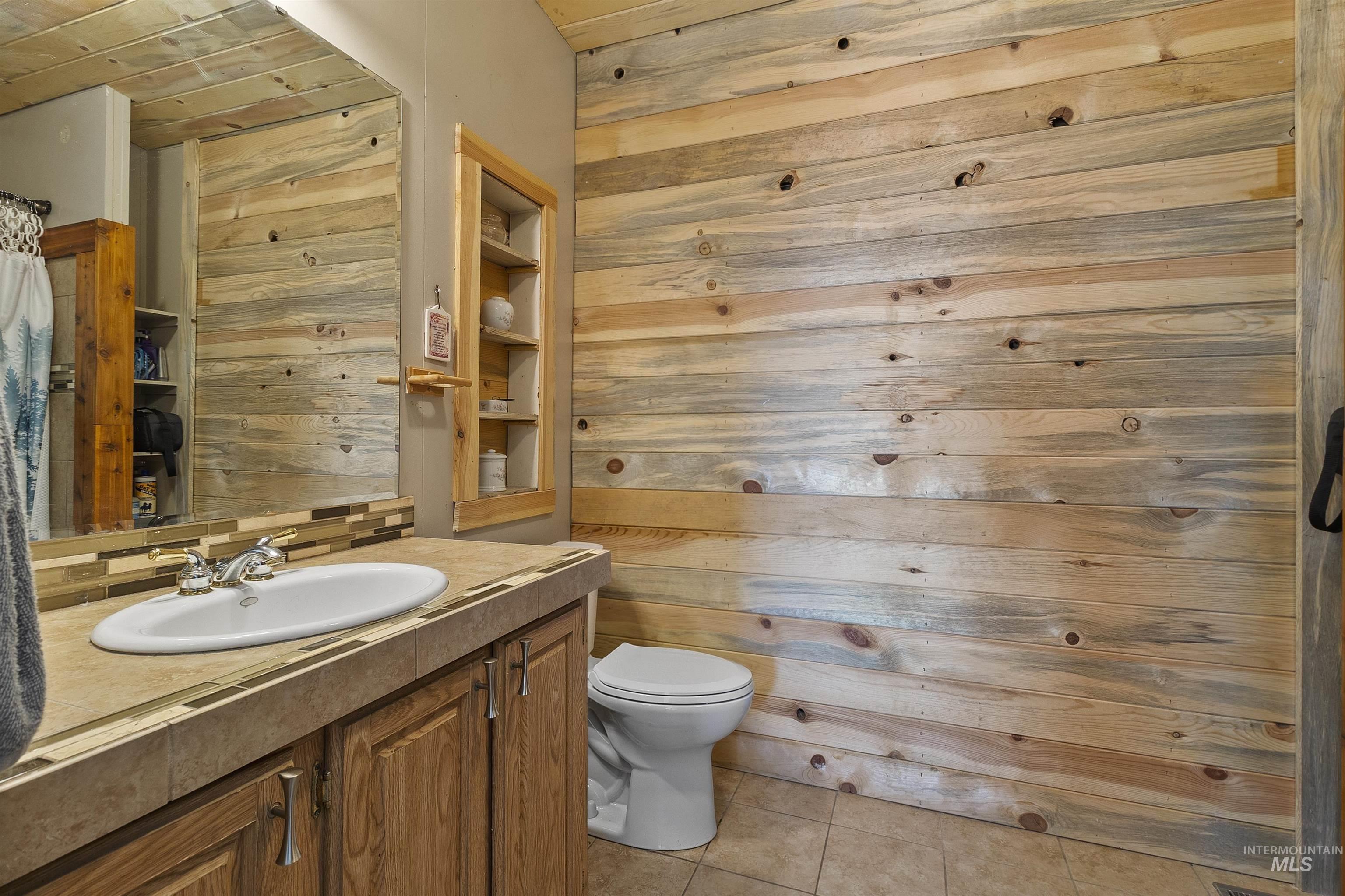 1311 Gold Hill Road Princeton, ID 83857 - Photo 17 of 25 Bathroom featuring vanity, wood walls, light tile patterned floors, and backsplash