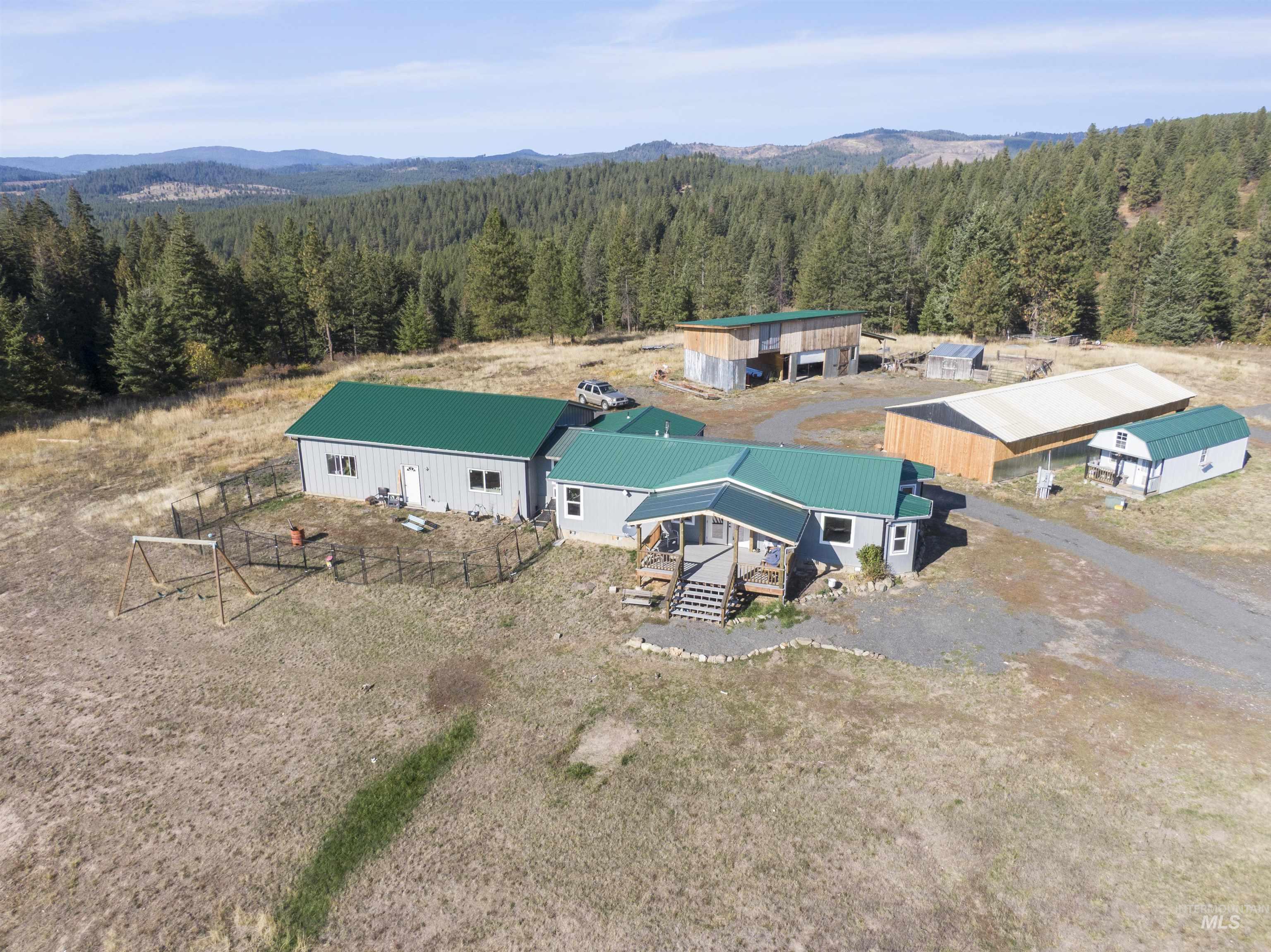 1311 Gold Hill Road Princeton, ID 83857 - Photo 20 of 25 Aerial view of property and surrounding area featuring a heavily wooded area and a mountain backdrop