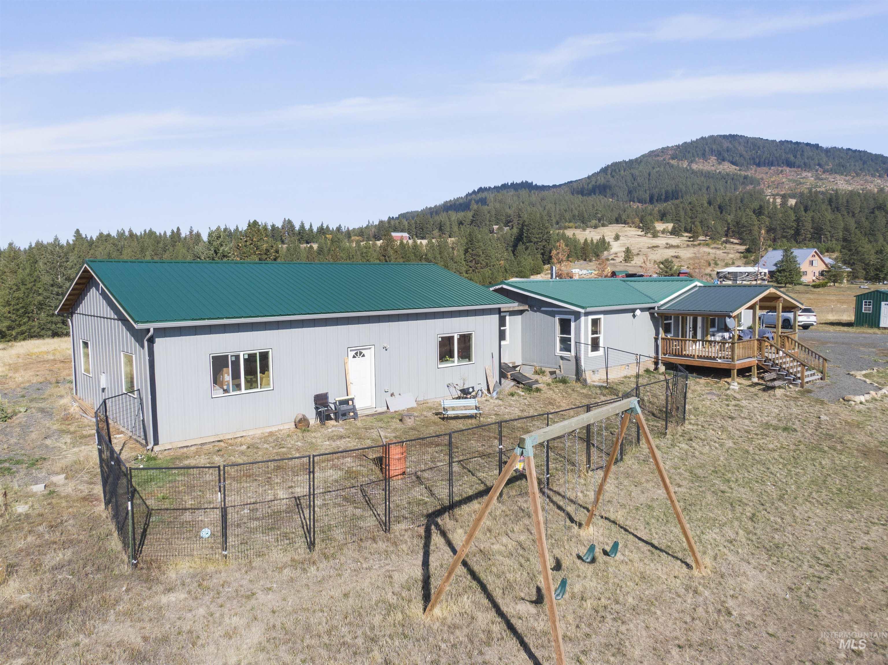 1311 Gold Hill Road Princeton, ID 83857 - Photo 22 of 25 Rear view of property with a metal roof, a mountain view, and a playground