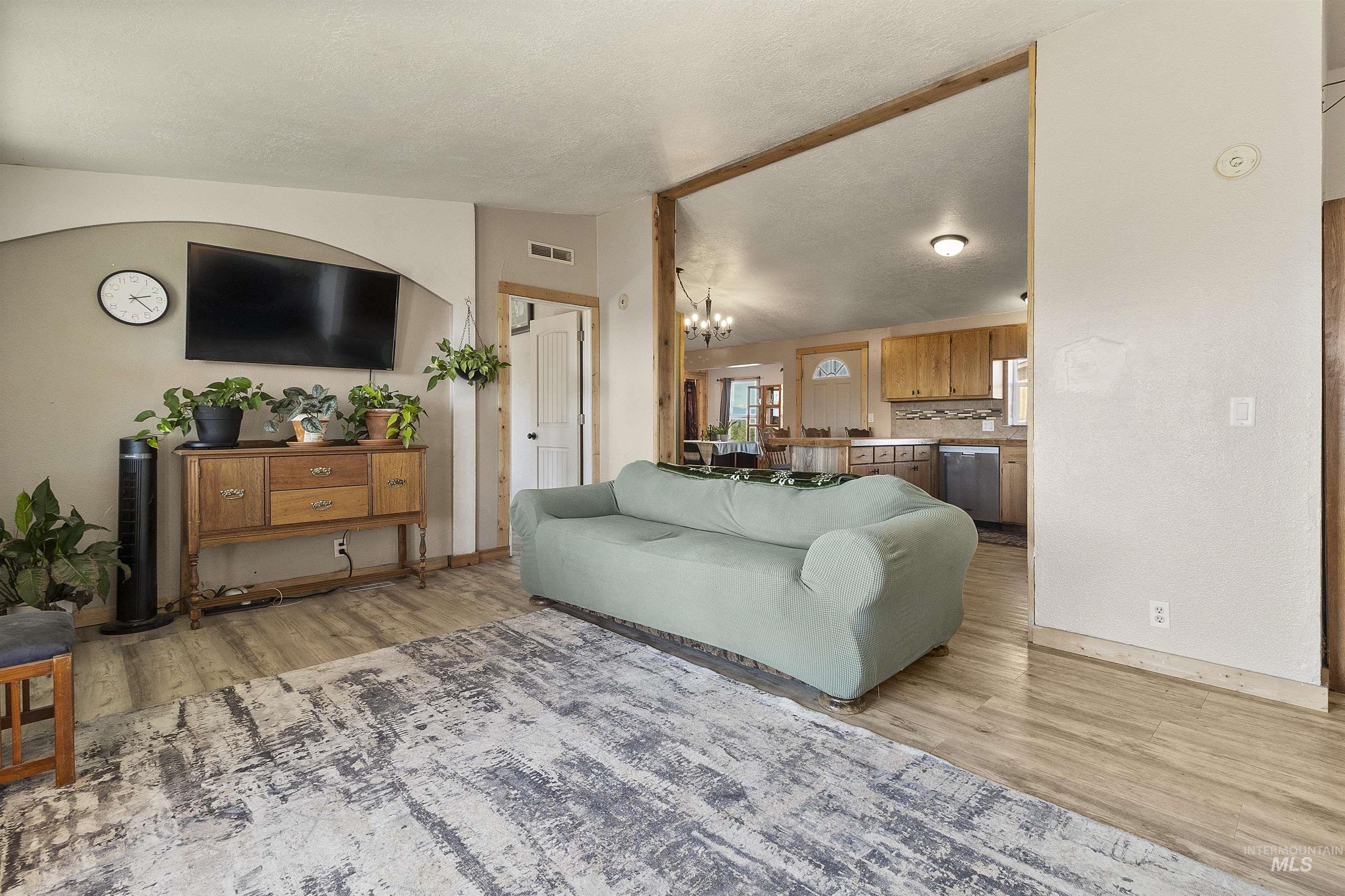 1311 Gold Hill Road Princeton, ID 83857 - Photo 3 of 25 Living room featuring a chandelier, vaulted ceiling, light wood finished floors, and a textured ceiling