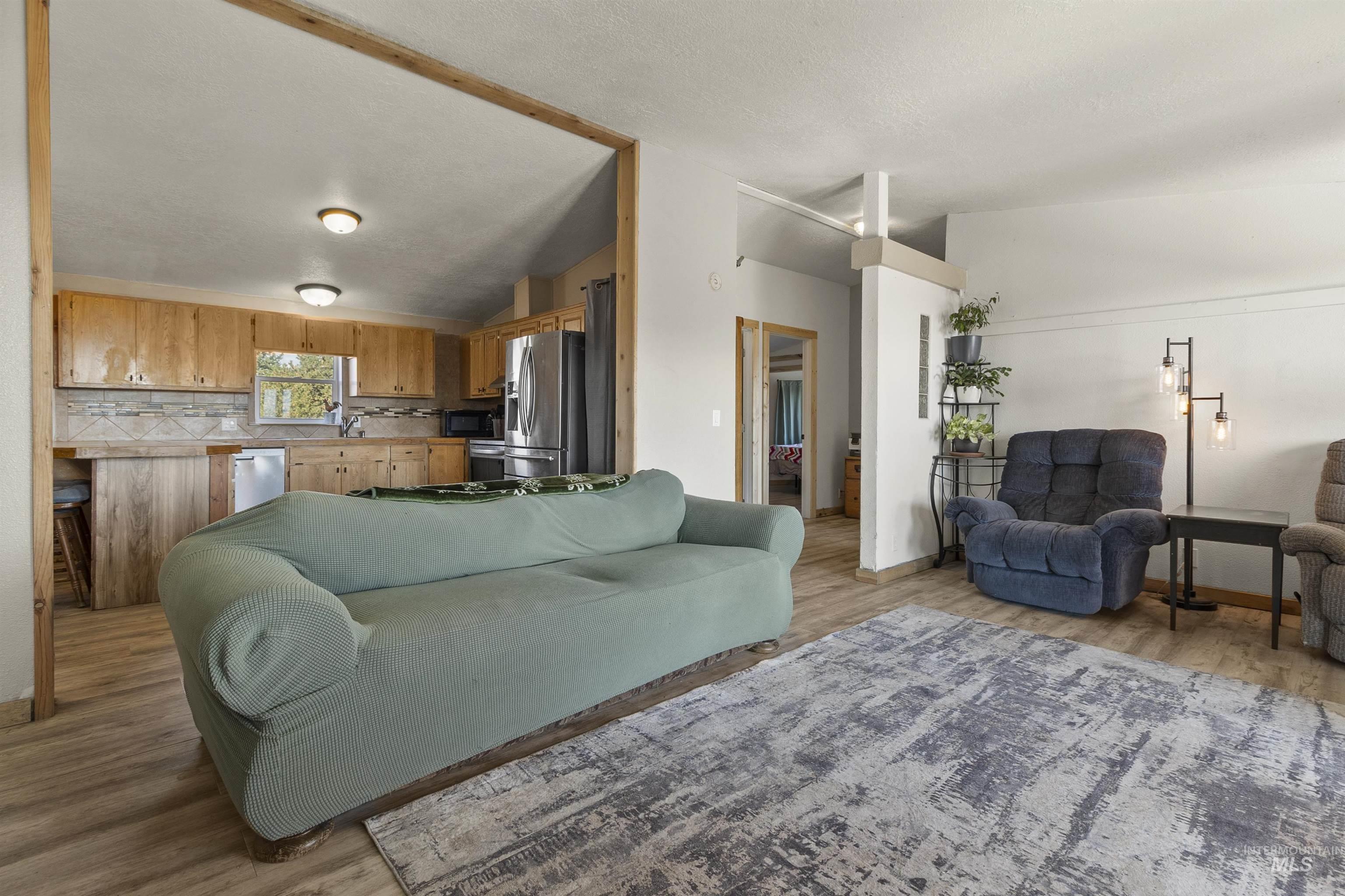 1311 Gold Hill Road Princeton, ID 83857 - Photo 4 of 25 Living room featuring lofted ceiling, light wood-style flooring, and a textured ceiling