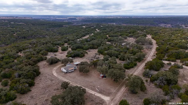 an aerial view of residential house with parking and trees