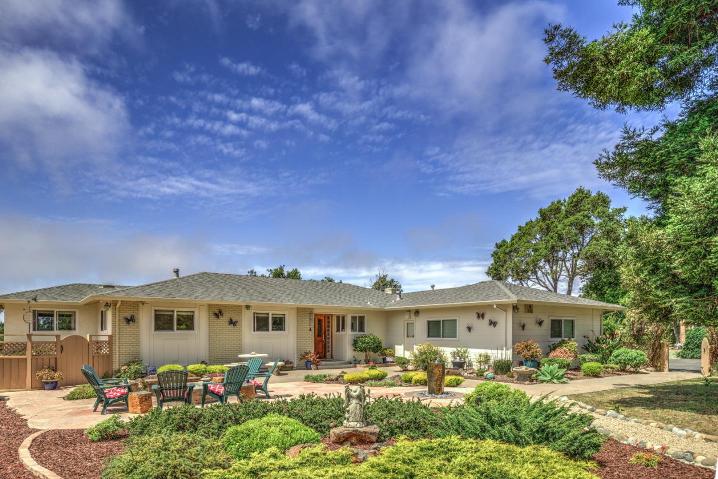 a front view of a house with garden and trees