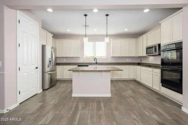 a large kitchen with cabinets stainless steel appliances a sink and a center island