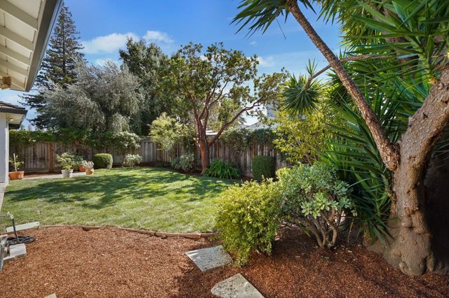 a backyard of a house with a garden and outdoor seating
