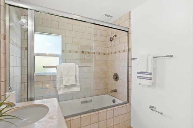 a bathroom with a tub shower and sink