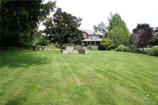 a view of a house with a big yard potted plants and large tree