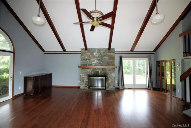 a view of an empty room with wooden floor fireplace and a window