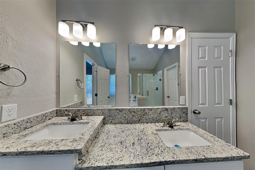 1703 Travis Court Allen, TX 75002 - Photo 11 of 21 Bathroom featuring a shower stall, a textured wall, and double vanity
