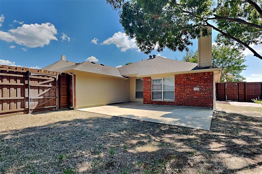 1703 Travis Court Allen, TX 75002 - Photo 20 of 21 Back of property with a gate, a chimney, brick siding, and a shingled roof