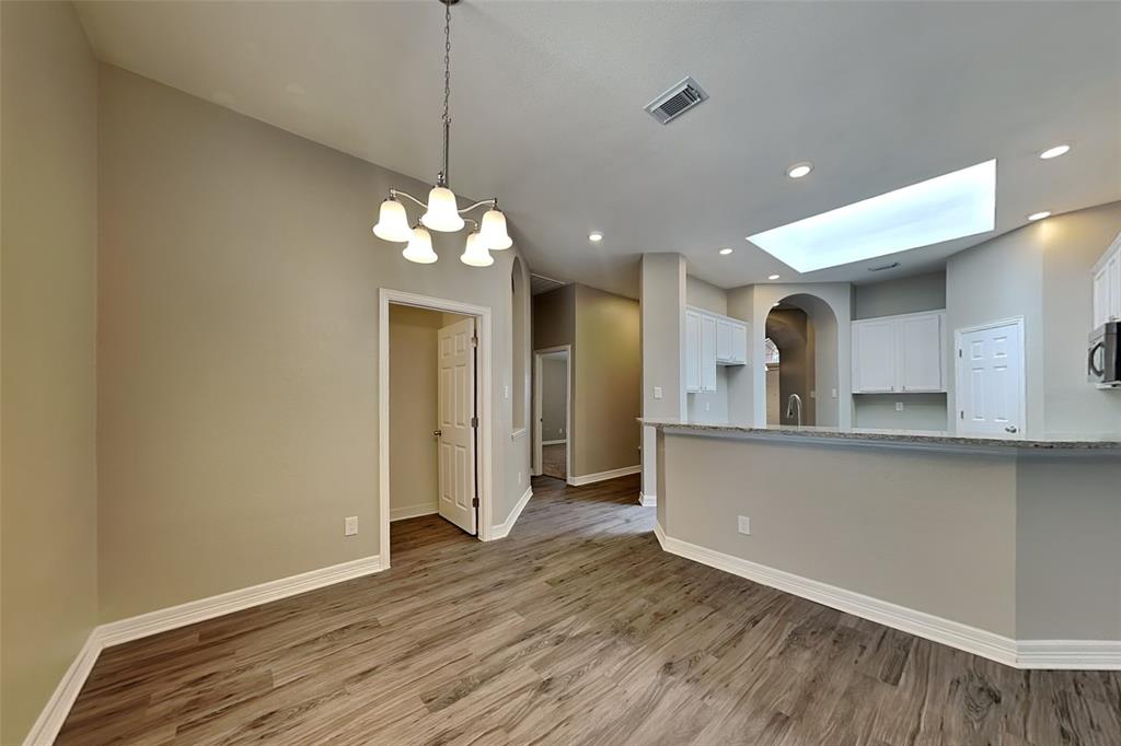 1703 Travis Court Allen, TX 75002 - Photo 6 of 21 Kitchen with light wood-type flooring, white cabinets, arched walkways, pendant lighting, and recessed lighting