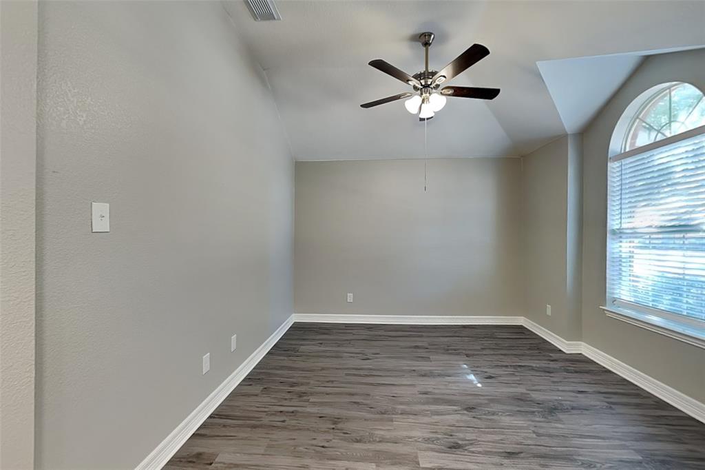 1703 Travis Court Allen, TX 75002 - Photo 7 of 21 Unfurnished room with vaulted ceiling, dark wood-type flooring, and ceiling fan
