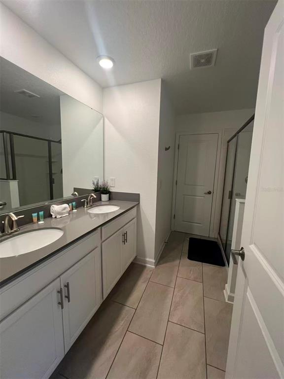 2940 Simile Street Kissimmee, FL 34746 - Photo 41 of 51 a spacious bathroom with a double vanity sink a mirror and a shower