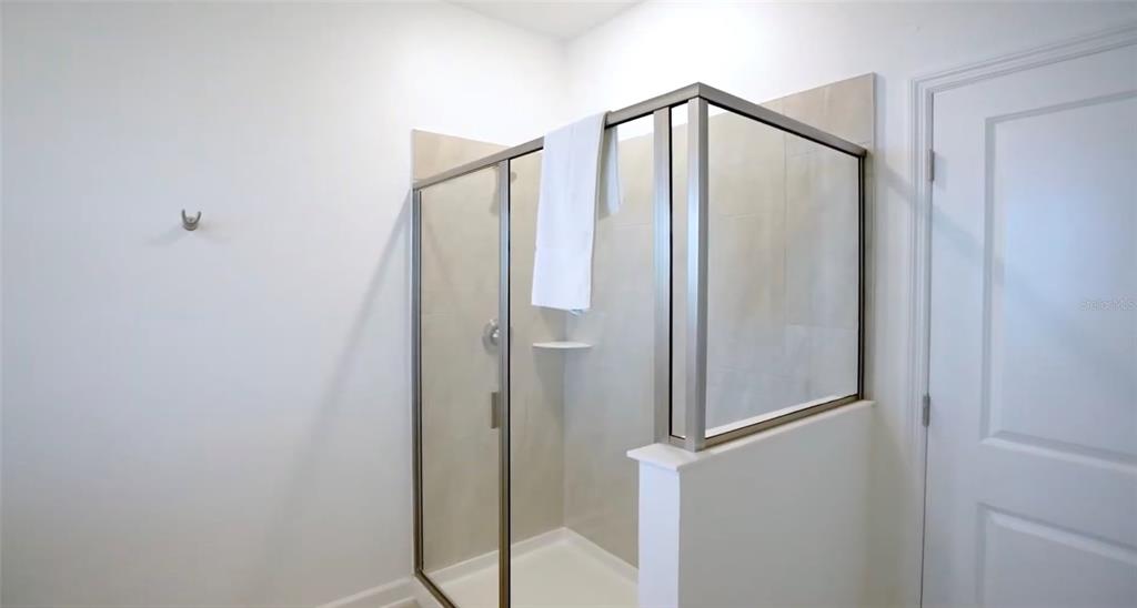 2940 Simile Street Kissimmee, FL 34746 - Photo 47 of 51 a bathroom with a glass shower door and a mirror