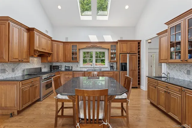 a kitchen with stainless steel appliances granite countertop a stove a sink dishwasher and a refrigerator with wooden cabinets