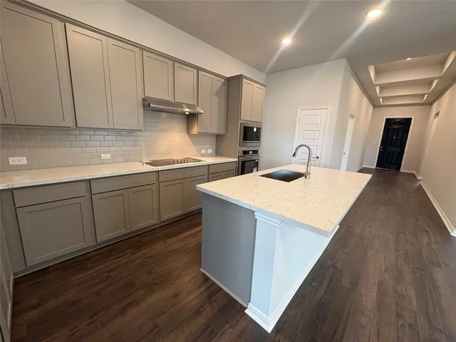 a kitchen with kitchen island a sink wooden floor and a refrigerator