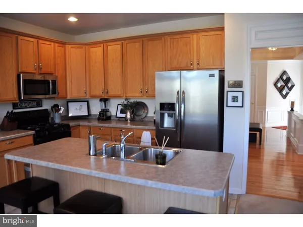 a kitchen with kitchen island a counter top space a sink a refrigerator and cabinets