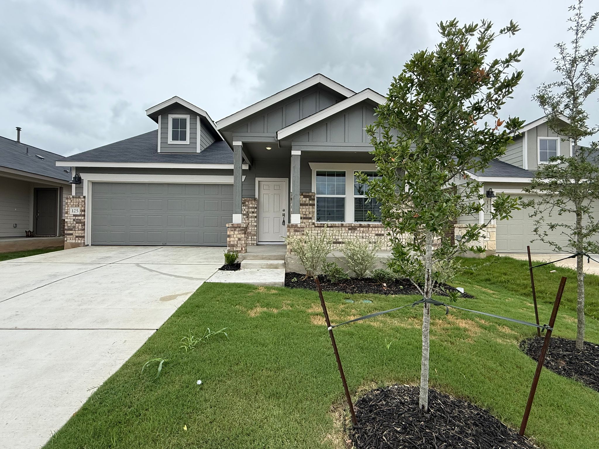 125 Sormonne Loop Kyle, TX 78640 - Photo 5 of 35 Craftsman-style home featuring board and batten siding, a front lawn, an attached garage, and concrete driveway