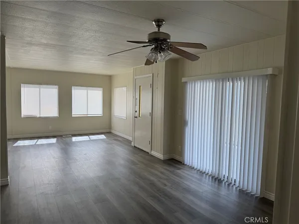 an empty room with wooden floor fan and windows