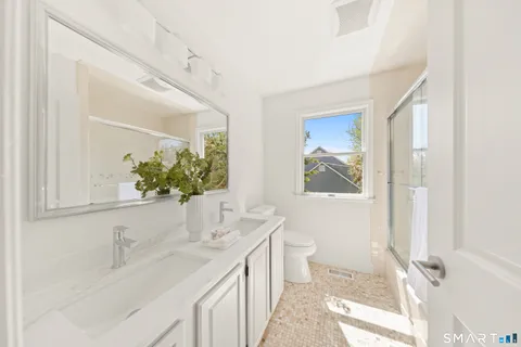 a bathroom with a granite countertop sink mirror vanity and toilet