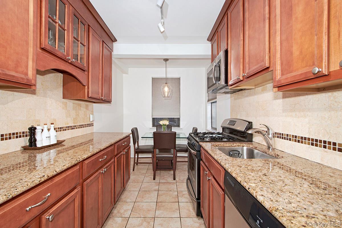 142 Garth Road, Unit 2M Scarsdale, NY 10583 - Photo 5 of 12 a kitchen with stainless steel appliances granite countertop a sink stove and cabinets