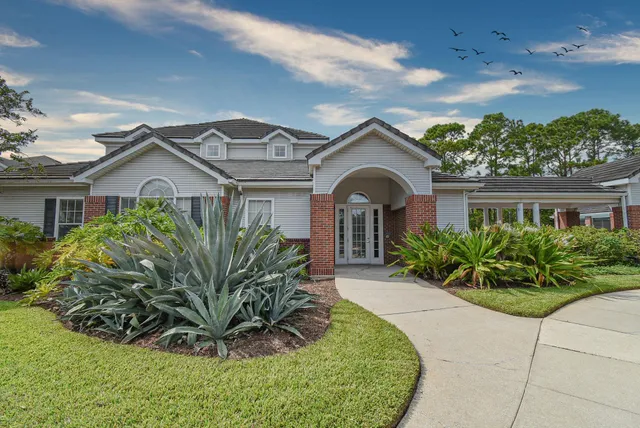 a living room with furniture a chandelier a large window and wooden floor