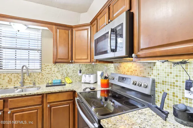 a kitchen with stainless steel appliances granite countertop a stove a sink and a microwave