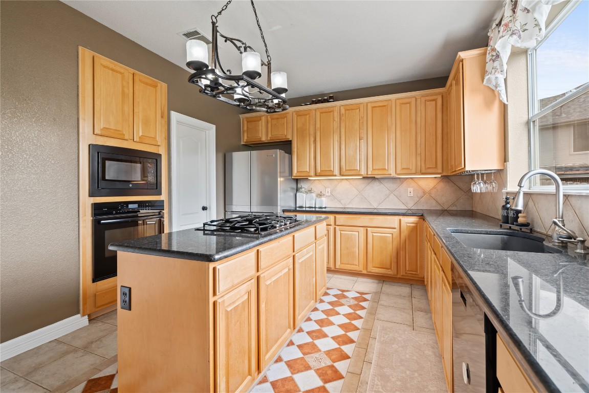 100 South Ridge Circle Georgetown, TX 78628 - Photo 11 of 37 Kitchen featuring backsplash, light brown cabinetry, a sink, black appliances, and a chandelier