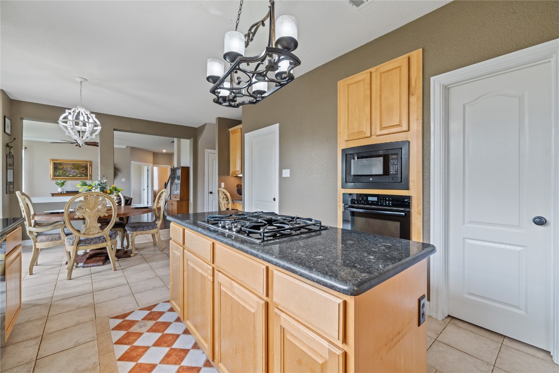 100 South Ridge Circle Georgetown, TX 78628 - Photo 12 of 37 Kitchen with a kitchen island, light tile patterned flooring, light brown cabinets, a chandelier, and black appliances