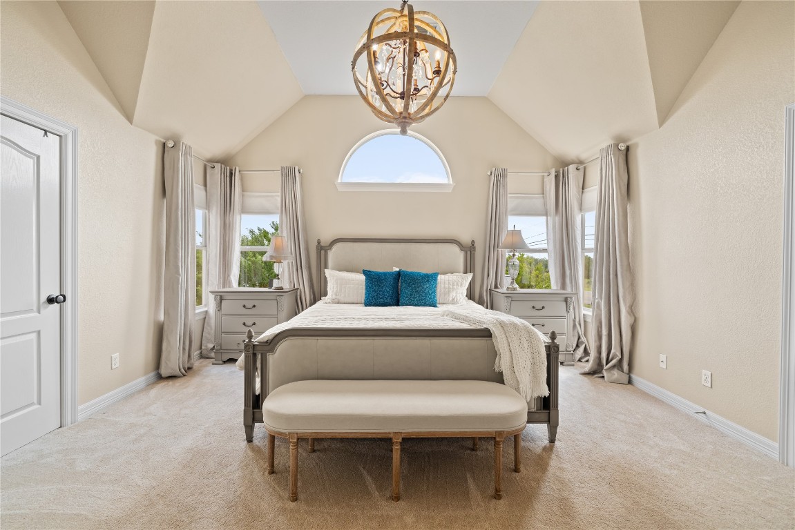100 South Ridge Circle Georgetown, TX 78628 - Photo 24 of 37 Bedroom featuring light colored carpet, baseboards, a notable chandelier, and vaulted ceiling