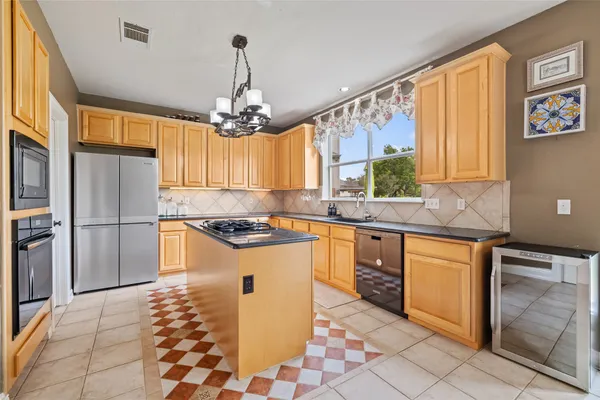 a kitchen with stainless steel appliances granite countertop a refrigerator a sink dishwasher a stove with wooden cabinets and floor