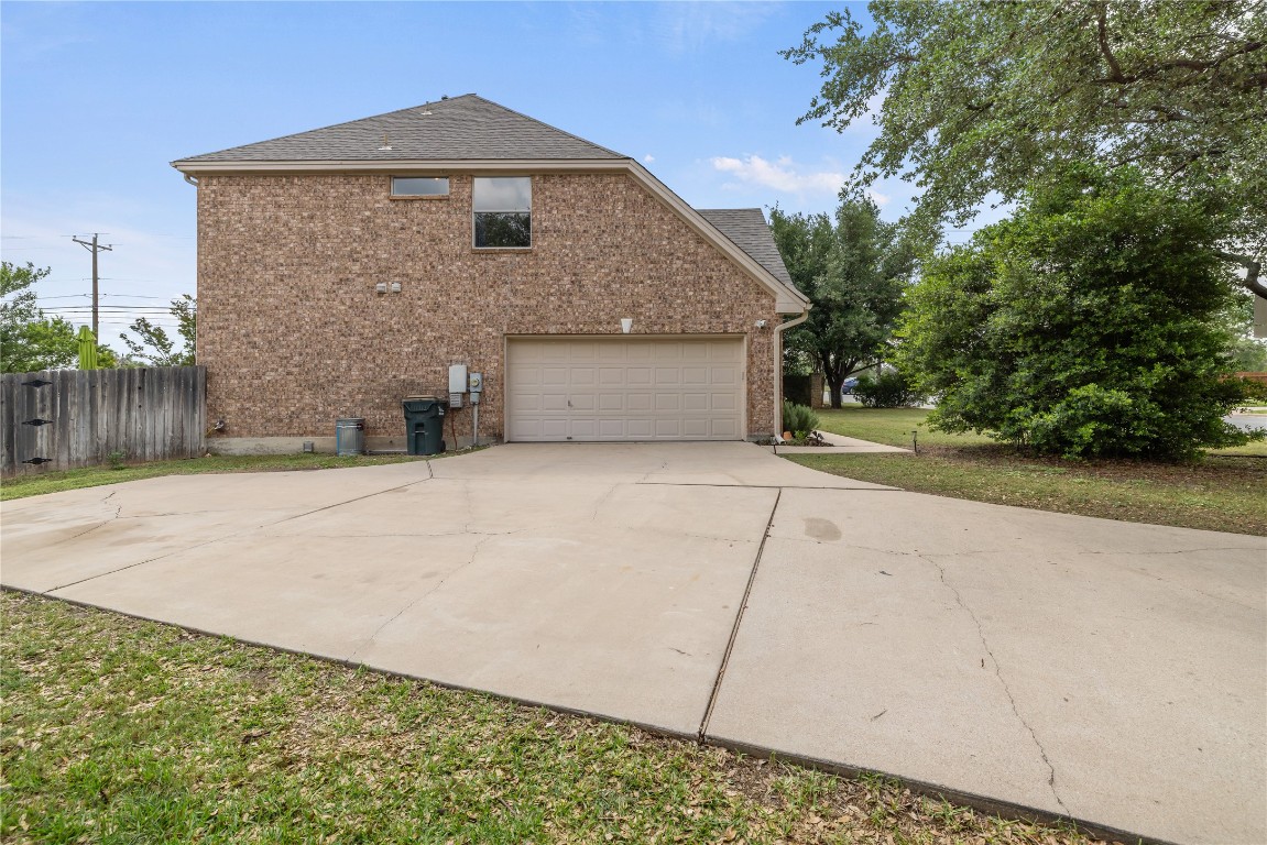 100 South Ridge Circle Georgetown, TX 78628 - Photo 37 of 37 View of side of home with driveway, a garage, brick siding, fence, and a shingled roof