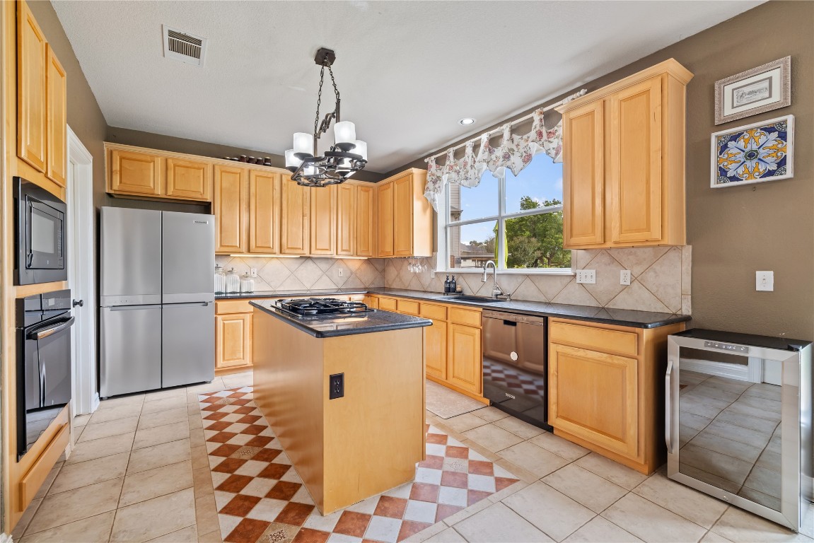 100 South Ridge Circle Georgetown, TX 78628 - Photo 10 of 37 Kitchen featuring light brown cabinetry, dark countertops, wine cooler, visible vents, and black appliances