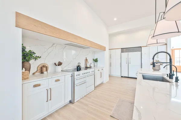 a large white kitchen with cabinets a sink and appliances