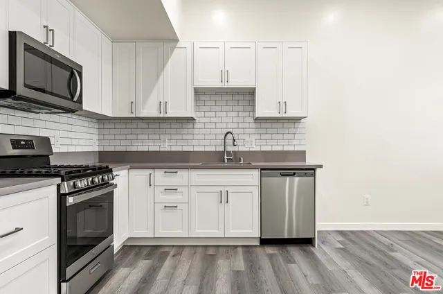 a kitchen with stainless steel appliances granite countertop a stove a sink and a microwave