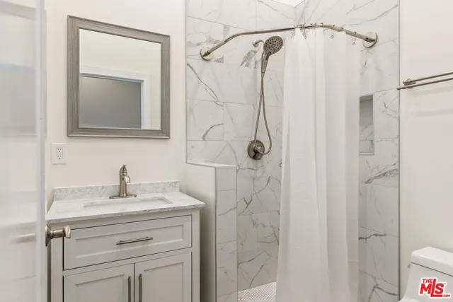 a bathroom with a shower sink vanity and mirror