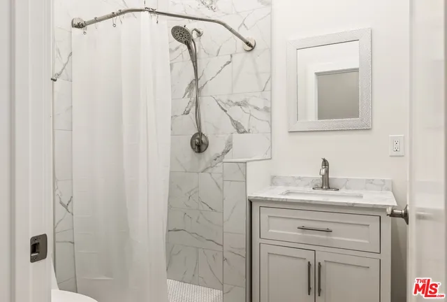 a bathroom with a sink vanity and shower